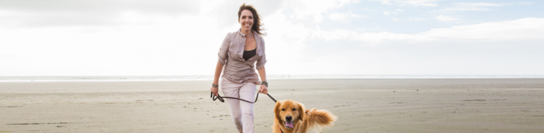 Woman on a beach walking her dog.